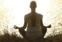 woman in front of water in a meditation pose