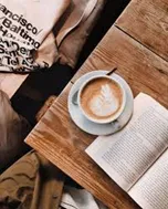 Coffee cup on a wooden table with a book.
