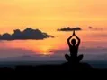 a person meditating in front of a sunset