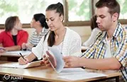 Adult students sitting at desk taking notes and reading.