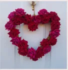 Wreath in the shape of heart decorated with red flowers.
