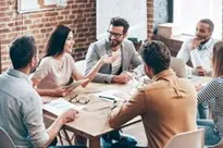Group of adults around a table talking.