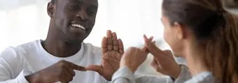 Two adults communicating with sign language. 