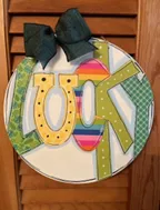 Round sign with "Lucky"  in multi colors and a ribbon on top.