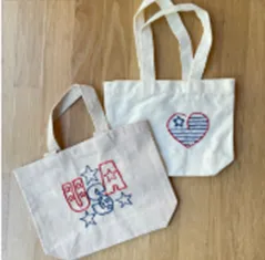 Two embroidered  canvas bags with "USA" and a patriotic heart on them.