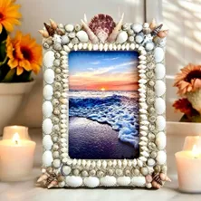 Sea shell frame surrounded by flowers and candles.
