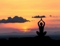 a person meditating in front of a sunset