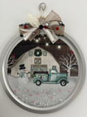 Winter scene with blue pickup truck, snowman, white barn decorated on a pizza pan.