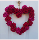Wreath in the shape of heart decorated with red flowers.