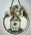 Spring decorative sign with "Home" on top of bird house with little blue bird eggs.
