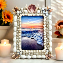 Sea shell frame surrounded by flowers and candles.